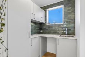 カイコウラにあるOcean Vista Hideawayの白いキャビネットと窓のあるキッチン