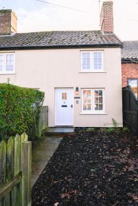 una casa bianca con una porta bianca e una recinzione di Daisy Cottage - Framlingham a Framlingham
