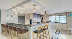 a woman in a kitchen with a bar with stools at Magnotel Harbin Songbei Wanda Wenlvcheng in Harbin