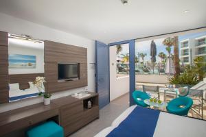 a bedroom with a bed and a tv and a balcony at Limanaki Beach Hotel & Suites in Ayia Napa