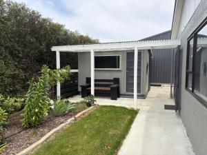 a patio with a couch under a white pergola at Just Dean Motueka in Lower Moutere