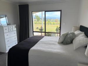a bedroom with a large bed with a large window at Just Dean Motueka in Lower Moutere