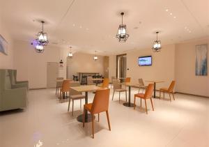 City Comfort Inn Wuhan International Expo Center Qianjin Village Metro Station في ووهان: غرفة طعام مع طاولات وكراسي وأضواء