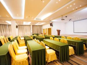 City Comfort Inn Zhanjiang Seaside Park Guanhai Corridor في زانجيانغ: غرفة مؤتمرات مع كراسي خضراء وصفراء وشاشة