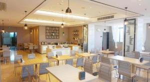 City Comfort Inn Zhanjiang Seaside Park Guanhai Corridor في زانجيانغ: مطعم به طاولات وكراسي في غرفة