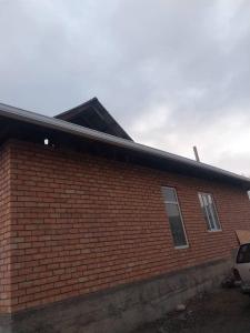 a red brick building with a car parked next to it at Nurdin Guest House in Kashkaldak