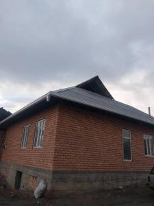 a red brick house with a black roof at Nurdin Guest House in Kashkaldak
