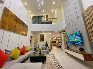 Una sala de estar con un sofá y un televisor en una pared. en Private Villa by YUSETH Residence, en Phumĭ Ta Phŭl