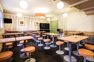 a restaurant with wooden tables and stools at ibis budget Chateaudun in Châteaudun