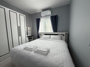 a bedroom with a white bed with two towels on it at Home Hug You in Chiang Mai