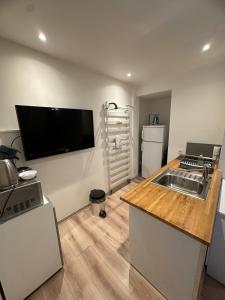 cocina con fregadero y TV de pantalla plana en la pared en Studio à 2 pas des thermes, en Saint-Martin-d'Uriage
