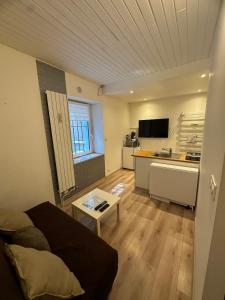 Una sala de estar con un sofá y una cocina. en Studio à 2 pas des thermes, en Saint-Martin-d'Uriage 7 fotos más