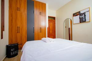 a bedroom with a white bed and wooden cabinets at The Cozy Nest in Kampala