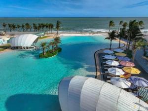 an aerial view of a resort pool with umbrellas and the ocean at Villa Malibu Tropicana , Nova Hồ Tràm in Ấp Thanh Bình