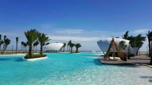 a pool with blue water and palm trees and white domes at Villa Malibu Tropicana , Nova Hồ Tràm in Ấp Thanh Bình