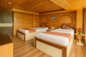Dos camas en una habitación con paredes de madera. en The Broadway- Annecy Inn Near Mall Road with -Wi-Fi -Restaurant -Premium &amp; Deluxe Rooms Prime Location - Best Top Rated Hotel In Darjeeling, en Darjeeling