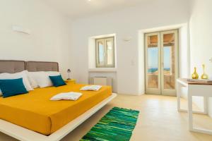 a bedroom with a large bed with yellow sheets and blue pillows at Villa Ftelia Boheme in Elia