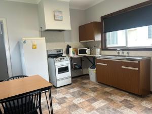 a kitchen with a refrigerator and a sink and a table at Bemm River Bungalows - Bellbird Abode - Bungalow 1 in Bemm River