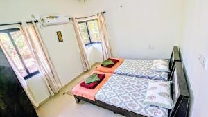 a bedroom with a bed and two windows at Redstone Hills, Diveagar in Diveagar