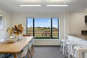 Un comedor con una mesa y un caballo en la ventana. en The Stables Lake and Country Retreat, en Taupo