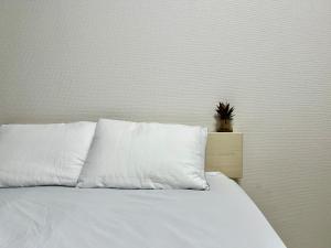 un letto bianco con cuscini bianchi e una pianta sopra di Apartment Hotel in Katsushika City a Tokyo