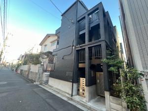 Un edificio nero sul lato di una strada di Apartment Hotel in Katsushika City a Tokyo