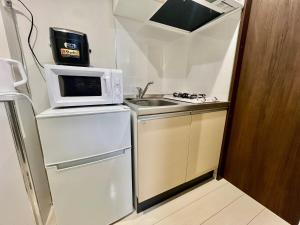 una piccola cucina con lavello e microonde di Apartment Hotel in Katsushika City a Tokyo