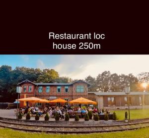 Ein Blockhaus mit Restaurant, in dem Menschen unter Sonnenschirmen sitzen. in der Unterkunft Appartements am Radweg stille Pauline in Fehrbellin in Fehrbellin