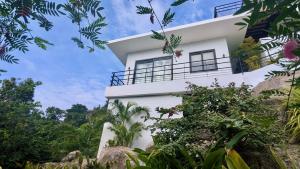 a white house with a balcony and trees at Titine Apartment in Srithanu +4 photos
