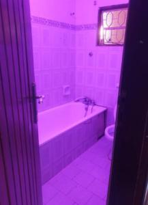 a pink bathroom with a tub and a toilet at KBK Comfort Accommodation in Kampala