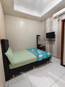 a small bedroom with a bed and a tv at Chill-Inn near Surabaya Zoo Syariah in Surabaya +19 photos