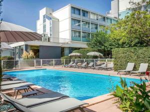 a swimming pool with lounge chairs and a building at Ibis Cavaillon Portes du Luberon in Cavaillon