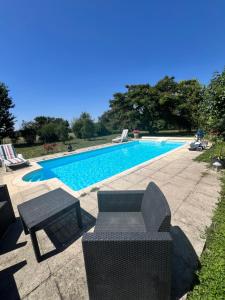 Una piscina con una mesa y sillas al lado. en Chez Paul, en Saint-Jean-de-Thurigneux