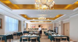 a woman standing in a dining room with tables at Vienna Hotel Shandong Dezhou Government Shopping Plaza in Songguantun