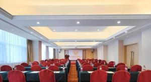 a conference room with red chairs and a podium at Vienna Hotel Shandong Dezhou Government Shopping Plaza in Songguantun