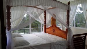 a bedroom with a canopy bed with a window at Tea Hills Bungalow in Hatton