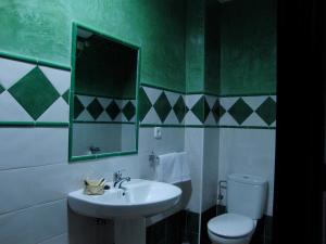 a green and white bathroom with a sink and a toilet at Hotel El Romeral in Almadén de la Plata