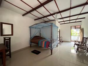 une chambre avec un lit à baldaquin dans une pièce dans l'établissement Vidara Guest House, à Weligama