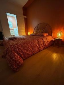 1 dormitorio con 1 cama con edredón rojo y ventana en Au Papillon, en Magenta