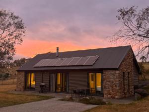 una piccola casa con pannelli solari sul tetto di Emu Rest Touchdown Cottages a Jindabyne