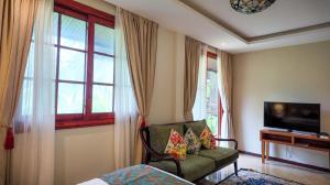 Viluveli Holiday Retreat في Hanimaadhoo: غرفة معيشة بها كرسي وتلفاز ونافذة