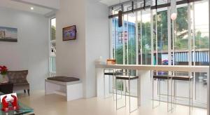 a living room with a bar with chairs and windows at Soontree House Hotel in Udon Thani