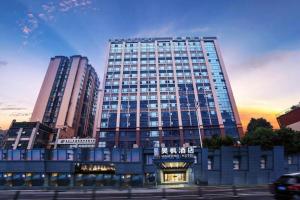 City Comfort Inn Chengdu Wenjiang University Town Fengxi River Metro Station في تشنغدو: مبنى طويل مع غروب الشمس أمامه