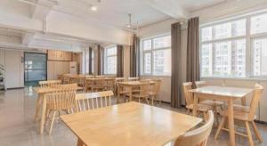 um restaurante com mesas e cadeiras de madeira e janelas em Borrman Hotel Dongguan Houjie Wanda Plaza Liaoxia Metro Station em Dongguan