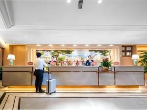 a man standing at a counter in a hotel lobby at Vienna Hotel Chongqing Wushan Municipal Government in Wushan