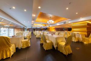 uma sala de jantar com mesas brancas e cadeiras amarelas em Century Plaza Hotel em Shenzhen