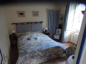 a bedroom with a bed with a blue and white comforter at Le Moulin d'Hys in La Cropte