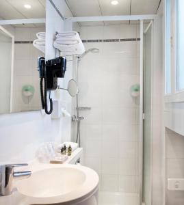 a white bathroom with a shower and a sink at Jack's Hotel in Paris