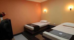 a small room with two beds and a television at Patria Palace Hotel in Blitar