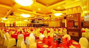 Un gran salón de banquetes con mesas rojas y sillas blancas. en Hotel Banjarmasin International, en Benuaanyar